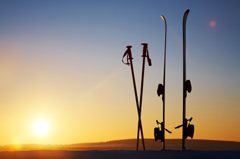 A set of skis and poles with a sunset in the background